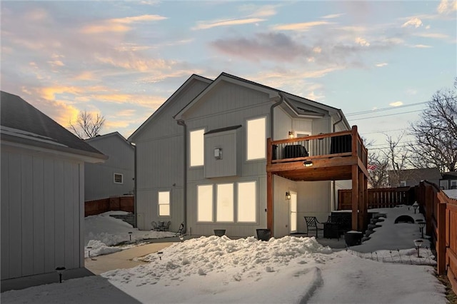 snow covered back of property with a balcony