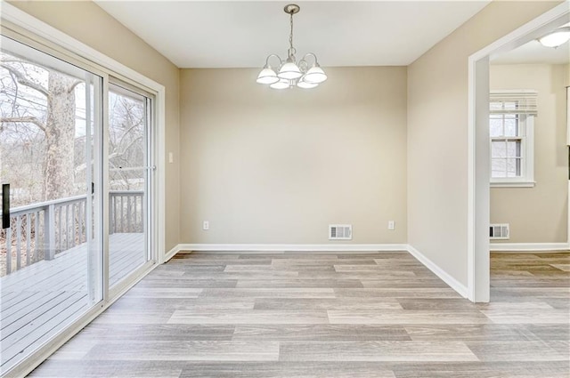 unfurnished dining area with an inviting chandelier and light hardwood / wood-style flooring