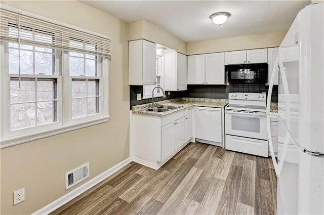 kitchen with white appliances, tasteful backsplash, light wood-type flooring, white cabinets, and sink