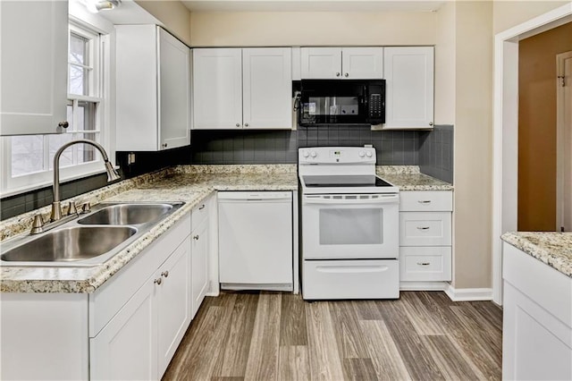 kitchen with white appliances, light wood-type flooring, white cabinets, backsplash, and sink