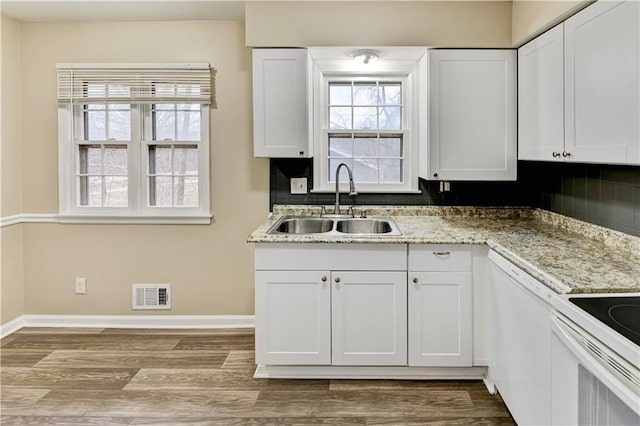 kitchen with sink, white cabinetry, dishwasher, light wood-type flooring, and light stone countertops