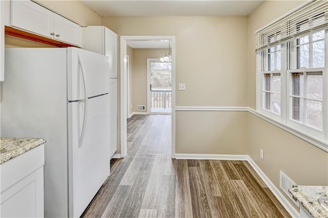 kitchen featuring white cabinets, white fridge, hardwood / wood-style floors, and plenty of natural light