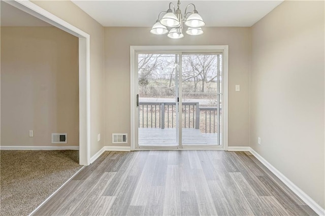 unfurnished dining area featuring a chandelier and hardwood / wood-style flooring