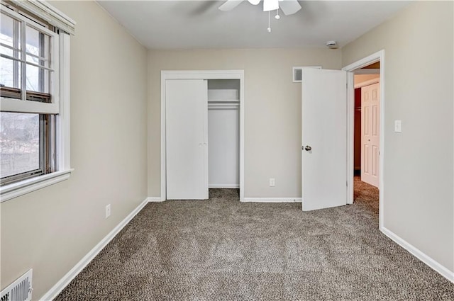 unfurnished bedroom with ceiling fan, a closet, multiple windows, and carpet floors