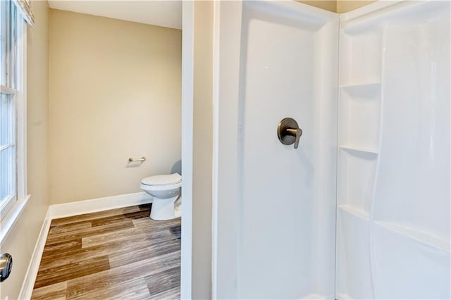 bathroom featuring walk in shower, hardwood / wood-style flooring, and toilet