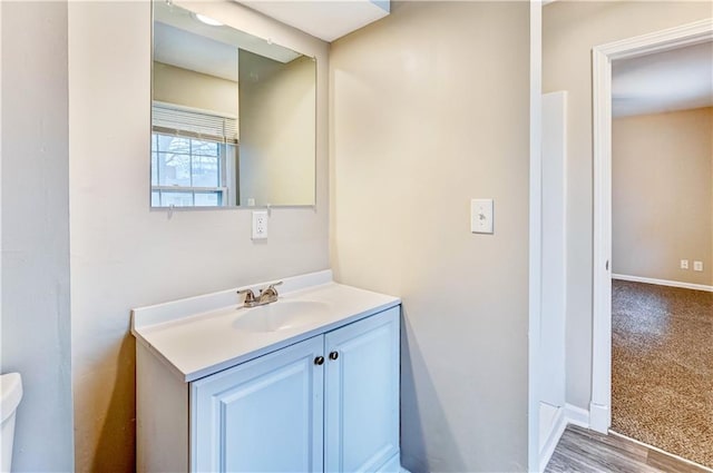 bathroom with toilet, hardwood / wood-style flooring, and vanity