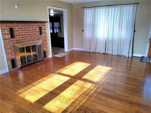 unfurnished living room with a brick fireplace and hardwood / wood-style flooring