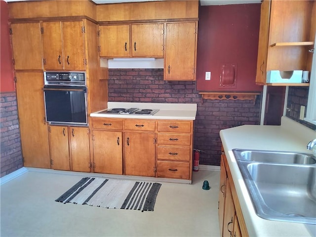 kitchen with sink, brick wall, gas stovetop, and oven