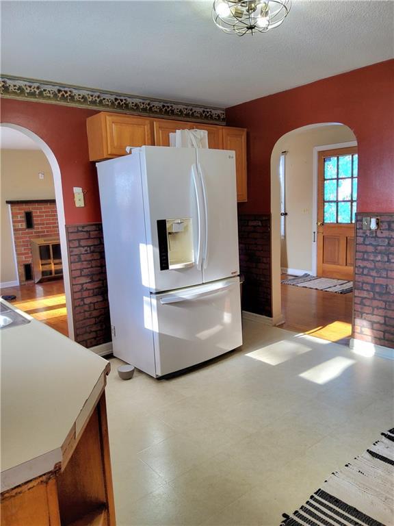 kitchen featuring brick wall, a brick fireplace, and white refrigerator with ice dispenser