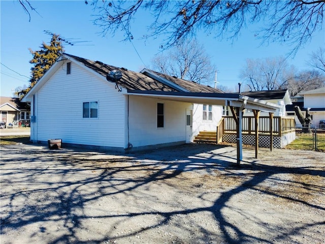 exterior space with a carport, a wooden deck, driveway, and fence