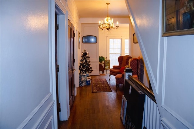 hallway with dark hardwood / wood-style flooring and an inviting chandelier