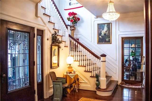 entrance foyer with dark wood-type flooring, crown molding, and an inviting chandelier