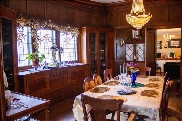 dining area featuring a notable chandelier and wooden walls