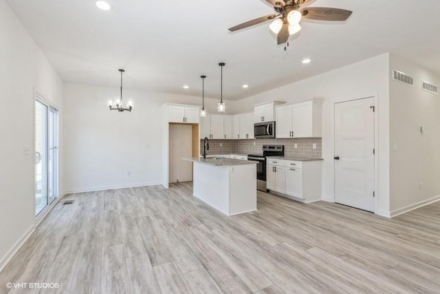 kitchen featuring white cabinets, light hardwood / wood-style floors, an island with sink, pendant lighting, and appliances with stainless steel finishes