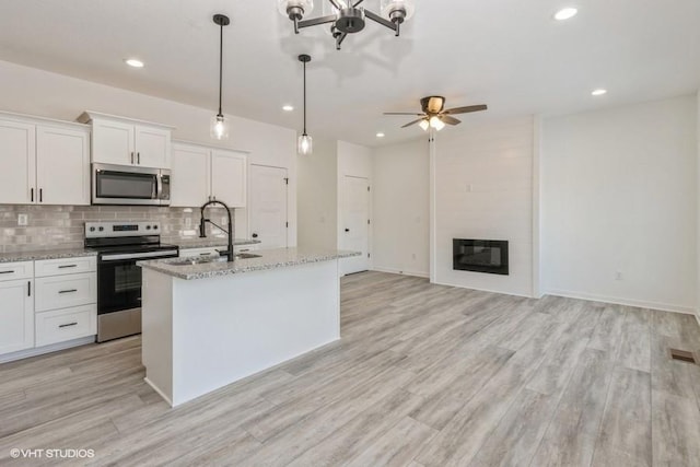 kitchen featuring sink, stainless steel appliances, white cabinetry, and a center island with sink