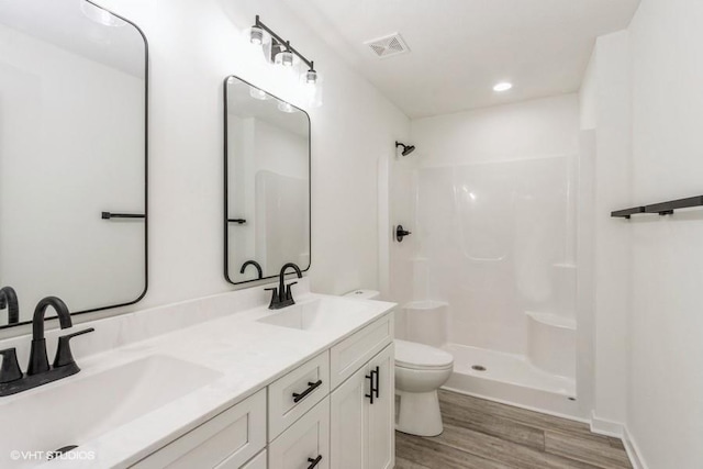 bathroom with toilet, walk in shower, vanity, and hardwood / wood-style flooring