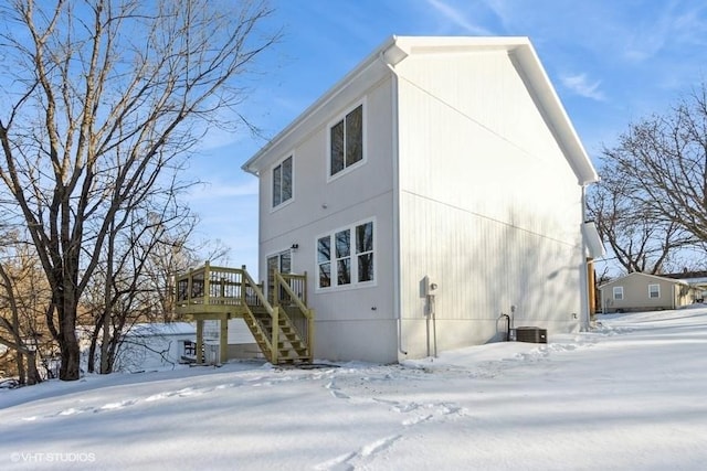 view of snowy exterior with a deck and central AC