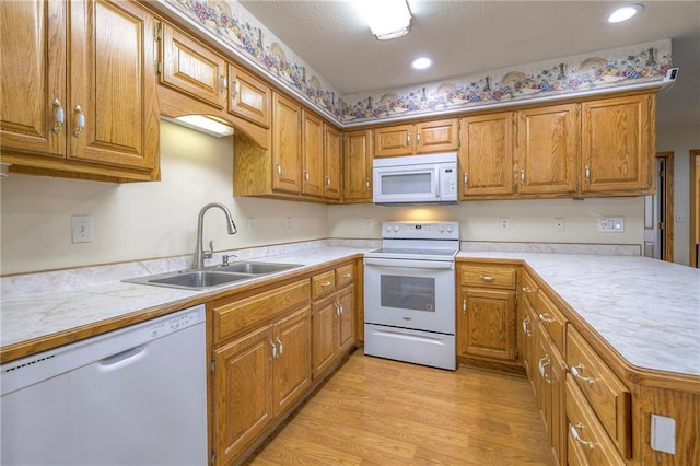 kitchen featuring sink, white appliances, and light hardwood / wood-style flooring