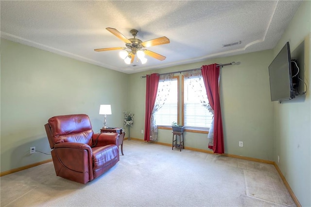 living area featuring light carpet, ceiling fan, and a textured ceiling