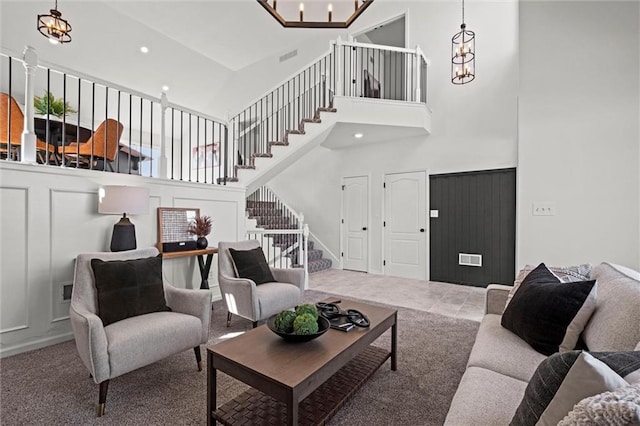 living area with stairs, carpet, a chandelier, and a decorative wall