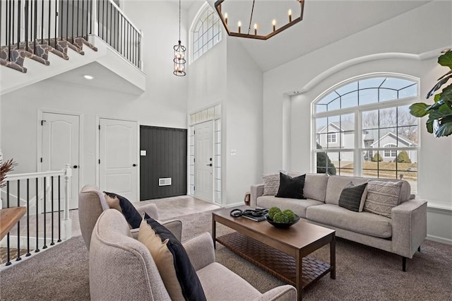 carpeted living area featuring a towering ceiling and a chandelier