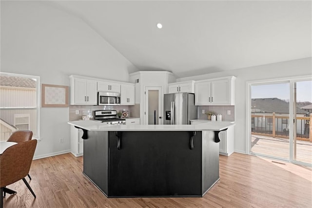 kitchen featuring stainless steel appliances, a breakfast bar, light countertops, and white cabinets