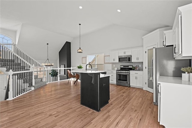 kitchen featuring a chandelier, light wood-style flooring, stainless steel appliances, light countertops, and a kitchen bar