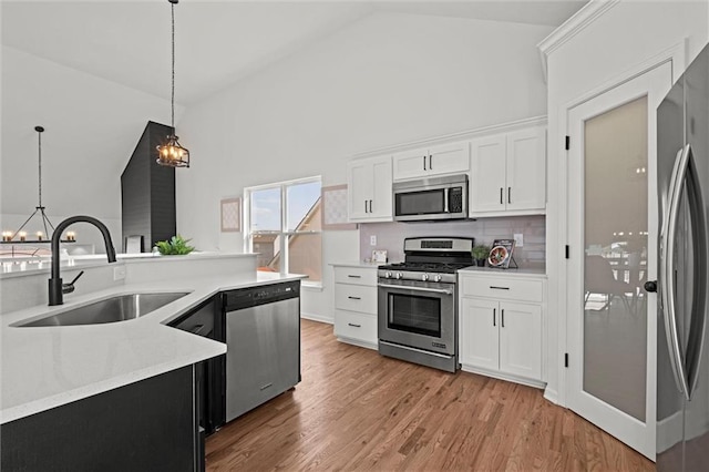 kitchen with decorative light fixtures, a sink, stainless steel appliances, light wood-style floors, and a notable chandelier