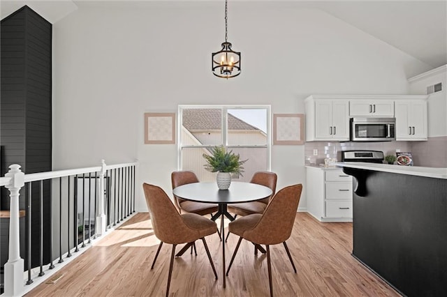 dining room featuring a chandelier, visible vents, high vaulted ceiling, and light wood finished floors