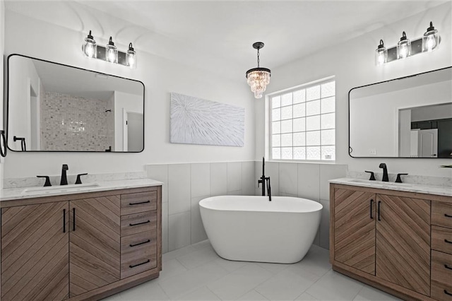 bathroom featuring a freestanding tub, two vanities, wainscoting, and a sink