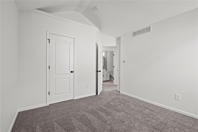 unfurnished bedroom with baseboards, visible vents, vaulted ceiling, and carpet flooring