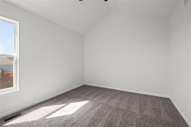 spare room featuring lofted ceiling, carpet floors, visible vents, and baseboards