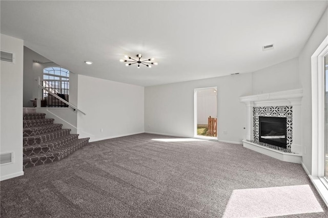 unfurnished living room featuring carpet floors, visible vents, stairway, and a tile fireplace