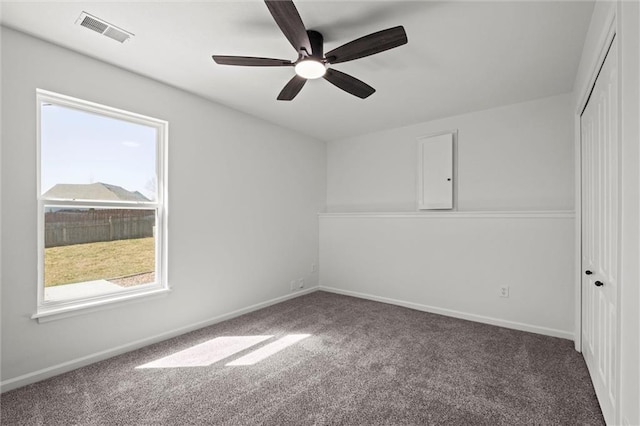 empty room with carpet floors, baseboards, visible vents, and ceiling fan