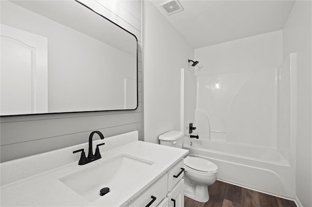 bathroom featuring visible vents, toilet, wood finished floors, tub / shower combination, and vanity