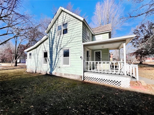 back of house with a lawn and covered porch