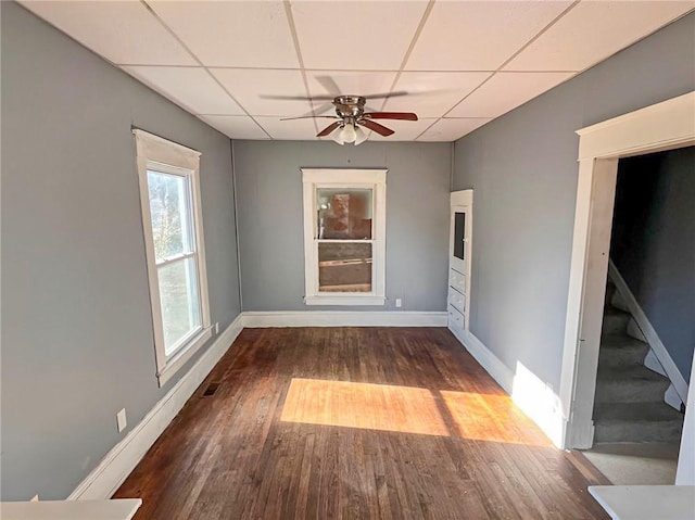 unfurnished room featuring ceiling fan, dark wood-type flooring, and a drop ceiling