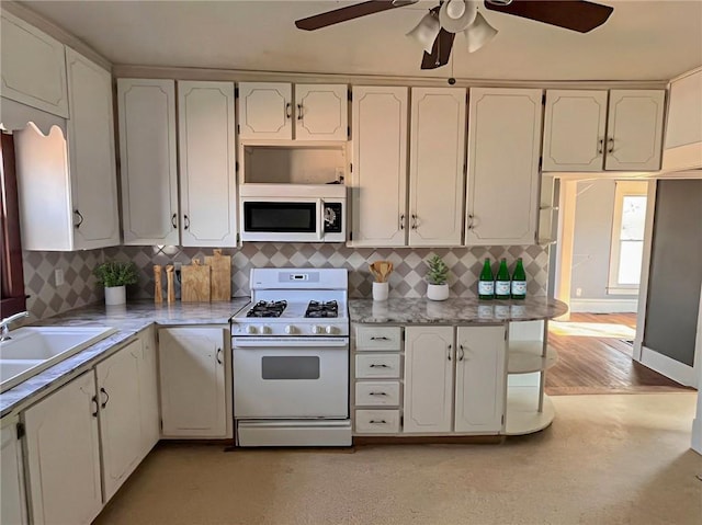 kitchen with white appliances, sink, and white cabinetry