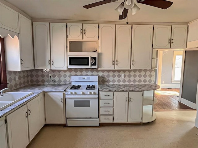 kitchen with white appliances, ceiling fan, white cabinets, and sink