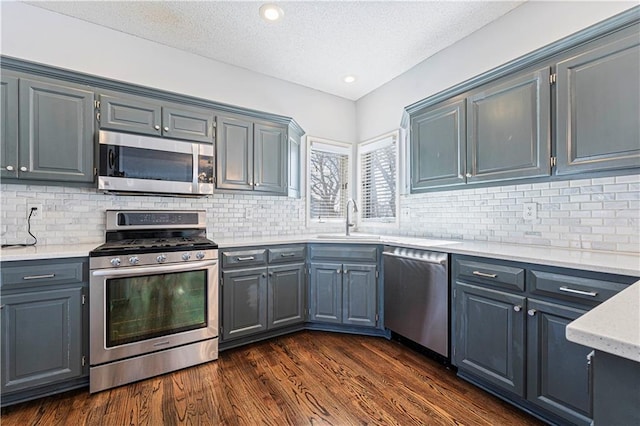 kitchen with sink, decorative backsplash, stainless steel appliances, dark wood-type flooring, and a textured ceiling