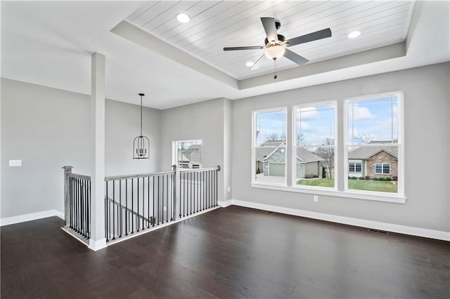 spare room with ceiling fan with notable chandelier, a raised ceiling, wooden ceiling, and dark hardwood / wood-style floors