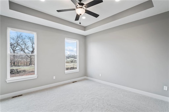 spare room with ceiling fan, a raised ceiling, and carpet floors