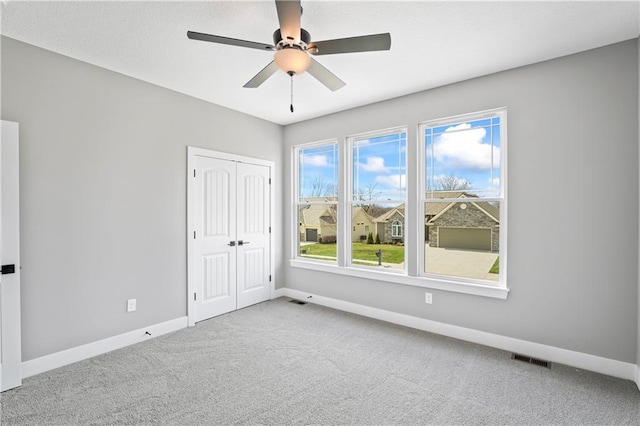 spare room with ceiling fan and light colored carpet