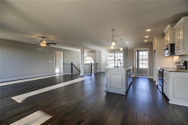 kitchen with appliances with stainless steel finishes, dark hardwood / wood-style floors, decorative light fixtures, sink, and a kitchen island with sink