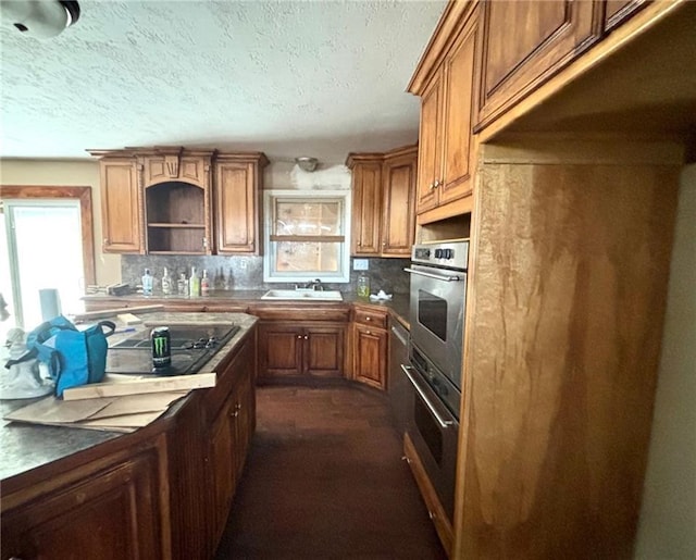 kitchen with stainless steel oven, a textured ceiling, tasteful backsplash, and sink