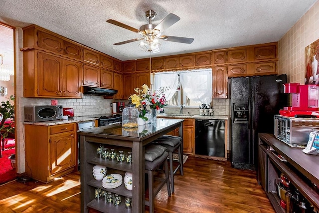 kitchen featuring sink, a textured ceiling, black appliances, and dark hardwood / wood-style flooring