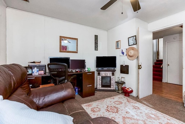 carpeted living room with ceiling fan and a fireplace