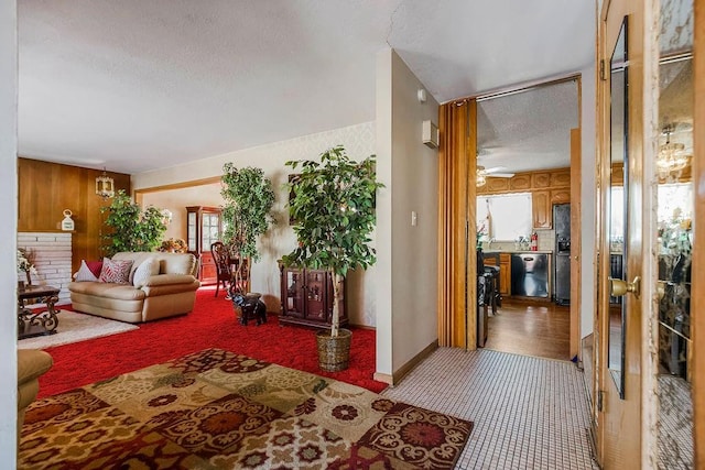 carpeted living room with ceiling fan, a textured ceiling, and wood walls