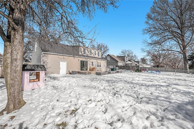 snow covered rear of property with central air condition unit and a storage unit