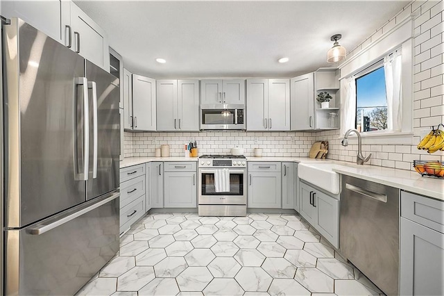 kitchen with decorative backsplash, sink, gray cabinets, and stainless steel appliances